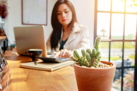 Asian business woman using calculator for accounting and analyzing investment in front of computer laptop at office workspace.  banking , savings , accountant , finances and economy concept.