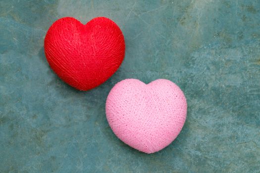 bright and colorful two handmade pink and red thread hearts on grey stone background Love, romance, together concept,