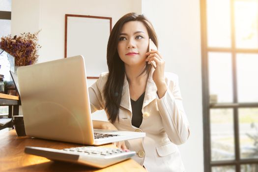 portrait of beautiful and confident Asian business woman in working age using computer laptop technology and smartphone for manage job work. businesswoman ,  girl power and International Women’s Day