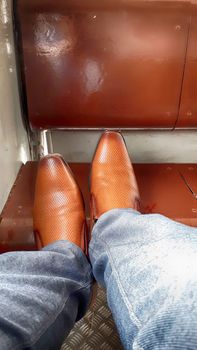 This is a picture of a man wearing a pair of brown shoes during a train travel.