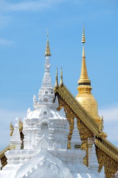 A white stucco gate, a temple with two tier roof, and a majestic golden pagoda of Wat Phra That Hariphunchai are seen from the east entrance. An iconic landmark of Lumphun city, Thialand
