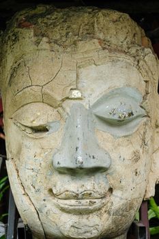 A beautiful ancient sandstone head of a Buddha's statue on displayed in public as religious relic at a temple in Chiang mai City, Thailand