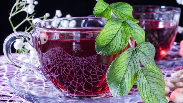 Hibiscus red tea mug with tea leaf or mint leaf close-up horizontal photo.Medicinal therapy on medicinal herbs and decoctions.Spicy herbs and medicinal broths.Relaxing and tonic drink.Zen tea ceremony