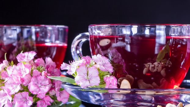 Hibiscus Red tea mug with carnation flowers close-up horizontal photo.English tea tradition.Medicinal therapy based on medicinal herbs and decoctions.Spicy herbs and medicinal broths.A relaxing drink