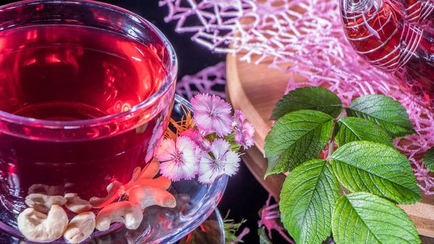 Hibiscus red tea mug with tea leaf or mint leaf close-up horizontal photo.Medicinal therapy on medicinal herbs and decoctions.Spicy herbs and medicinal broths.Relaxing and tonic drink.Zen tea ceremony