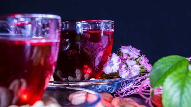 Hibiscus Red tea mug with carnation flowers close-up horizontal photo.English tea tradition.Medicinal therapy based on medicinal herbs and decoctions.Spicy herbs and medicinal broths.A relaxing drink