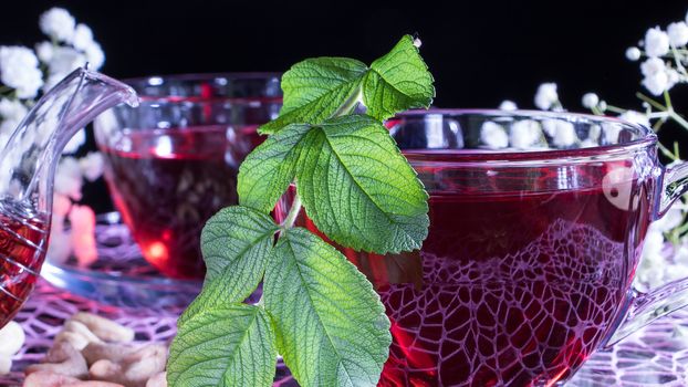 Hibiscus red tea mug with tea leaf or mint leaf close-up horizontal photo.Medicinal therapy on medicinal herbs and decoctions.Spicy herbs and medicinal broths.Relaxing and tonic drink.Zen tea ceremony