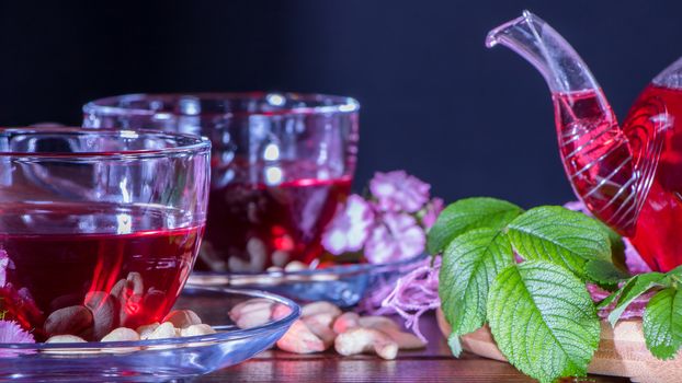 Hibiscus Red tea mug with carnation flowers close-up horizontal photo.English tea tradition.Medicinal therapy based on medicinal herbs and decoctions.Spicy herbs and medicinal broths.A relaxing drink