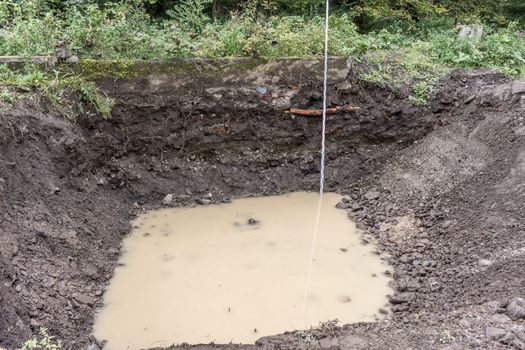 Building pit with groundwater ingress and measuring rod, Andreasberg, Harz mountains