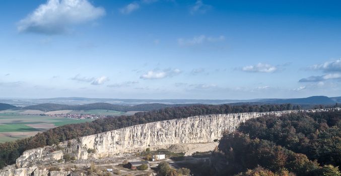 Aerial view of a quarry with a village in the background, blue sky with clouds