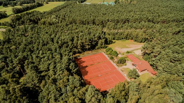 Aerial view of  tennis courts in a dense green forest