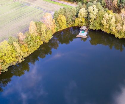 Fishing lodge in the corner of a pond, aerial view with drone