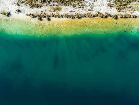 Abstract aerial view of the shore of a gravel pond with drone, vertical angle of view, a lot of space below