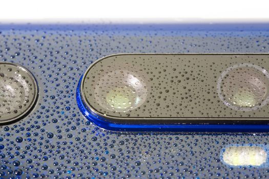 blue phone camera lens covered with small water drops - close-up with selective focus and blur.