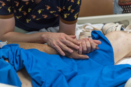 Patient in the hospital with saline intravenous and relatives patient hand holding a elderly patient hand