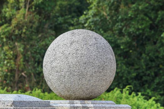 Close-up of an outdoor sphere marble stone work on staircase railling in public park with green nature background.