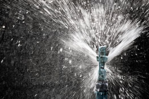 Close up view of sprinkler spraying water on blur background in garden.