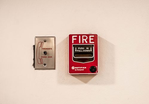 Red fire alarm switch on interior cement wall of Department Store building in Chiang Mai city. Safety concept.