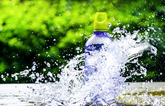 Fresh pure water splashing around of bottle with blurred background. Selective focus and space for text.