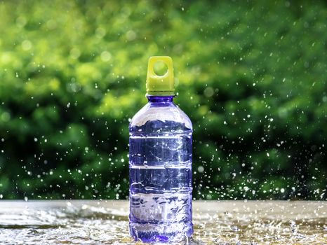 Fresh pure water splashing around of bottle with blurred background. Selective focus and space for text.