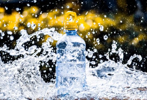 Fresh pure water splashing around of bottle with blurred background. Selective focus and space for text.