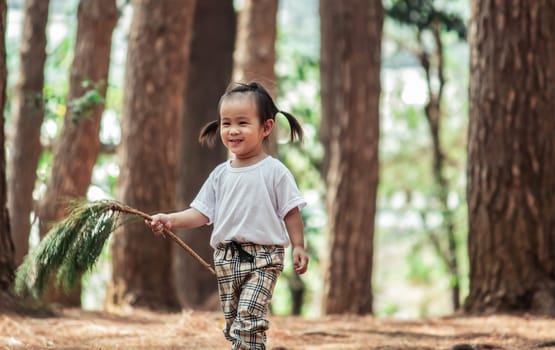 Asian little child girl walking in pine forest for studying the environment excitedly.