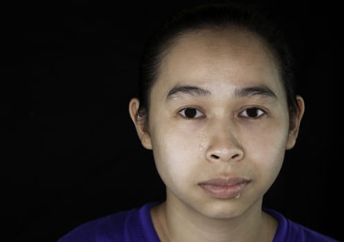 Close-up of The face of an Asian young woman who doesn't have makeup; isolated on black background.