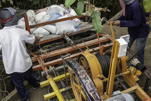 Construction workers are using electric winches to transport sandbags.