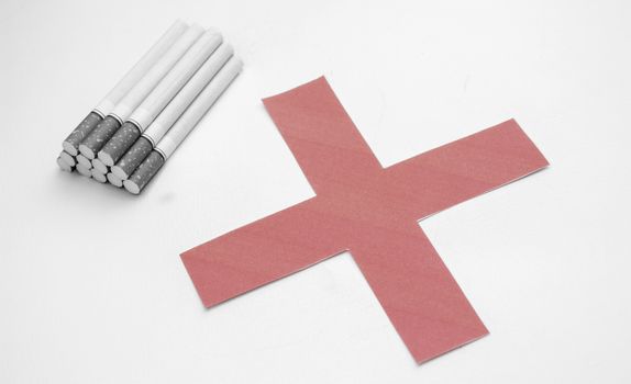 World No Tobacco Day; Heap of cigarettes with filter isolated on white background and Red cross symbol.