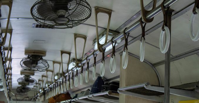 Close-up of Hand holding strap and Old fan  in the vintage diesel engine train of Thailand.