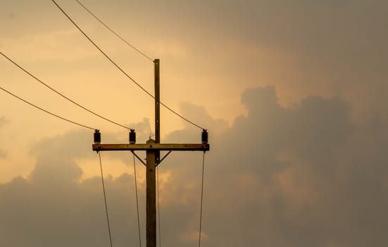 Electric poles with cables of electric on sunset background in evening