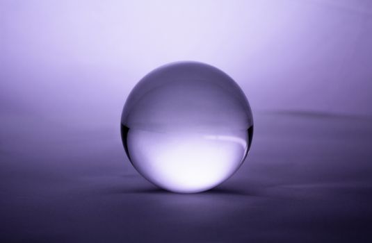 Crystal glass ball sphere transparent on purple gradient background.