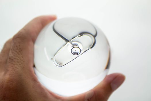 Close-up of Hand holding Crystal glass ball sphere revealing the inner medical stethoscope and syringe on grey gradient background.