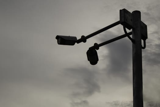 Closed circuit camera on dark gray dramatic sky with large clouds background.