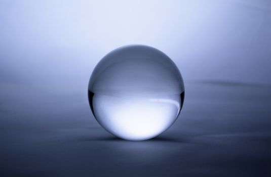 Crystal glass ball sphere transparent on blue gradient background.