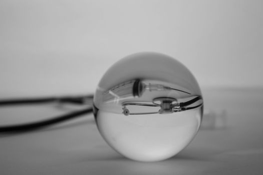 Crystal glass ball sphere revealing the inner medical stethoscope on grey gradient background.