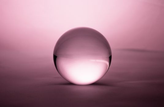 Crystal glass ball sphere transparent on pink gradient background.