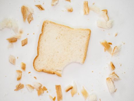 Scattered bread crumbs and Sliced Bread on white table background.