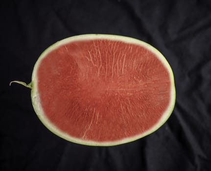 Top view of Watermelon, half-ball, bright red and seedless, placed on a black background.