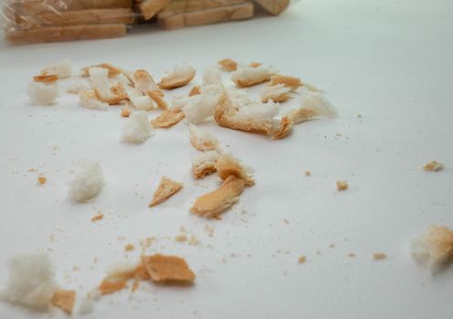 Scattered bread crumbs on white table background.