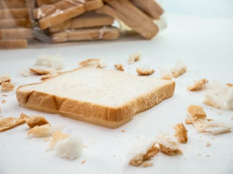 Scattered bread crumbs and Sliced Bread on white table background.