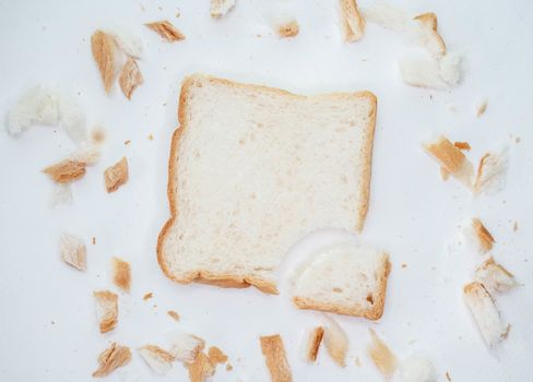 Scattered bread crumbs and Sliced Bread on white table background.