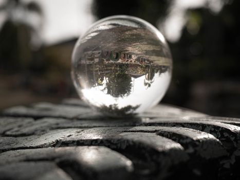 Crystal glass ball sphere place on tire rim and revealing the inner big tree on blurred background.