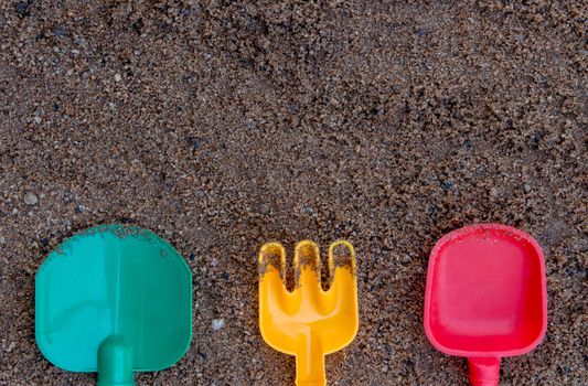Children's beach toys - buckets, spade and shovel on sand with space for your texts. Concept of happiness on summer and fun of children.