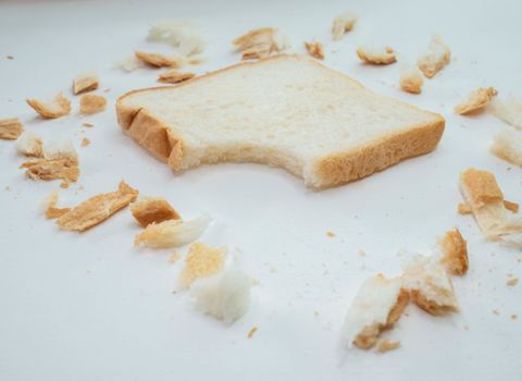Scattered bread crumbs and Sliced Bread on white table background.