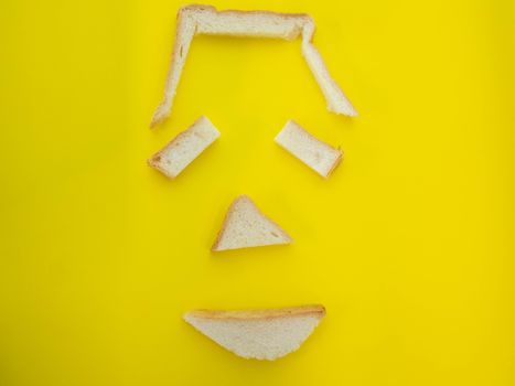 Bread crumbs placed as faces on yellow background.