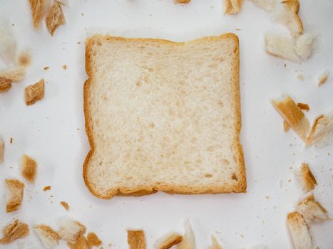 Scattered bread crumbs and Sliced Bread on white table background.