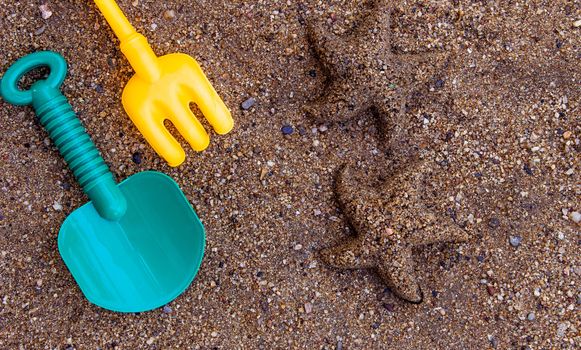 Children's beach toys - buckets, spade and shovel on sand with space for your texts. Concept of happiness on summer and fun of children.