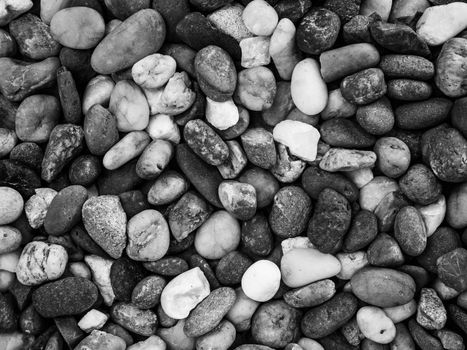 Pebbles pattern or small stones background in garden with copy space for your text. Black and white picture.