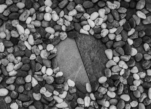 Pebbles pattern or small stones background in garden with copy space for your text. Black and white picture.